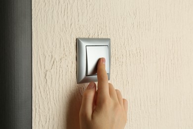 Photo of Woman turning light switch on, closeup view