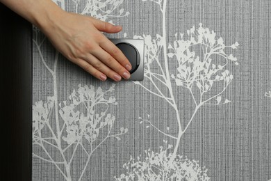 Photo of Woman turning light switch on, closeup view