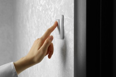 Photo of Woman turning light switch on, closeup view