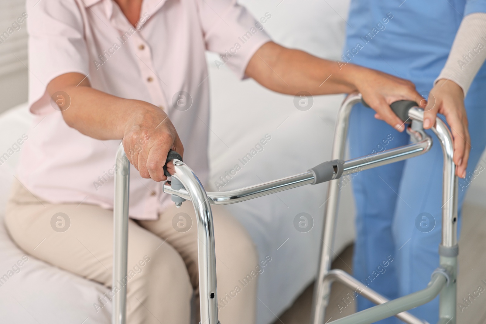 Photo of Nurse helping senior woman with walking frame in clinic, closeup