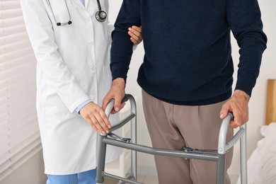 Photo of Doctor helping senior man with walking frame in clinic, closeup