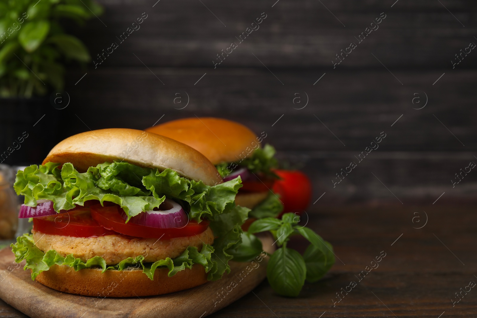 Photo of Delicious vegetarian burgers with chickpea cutlets on wooden table. Space for text