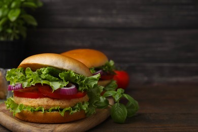 Photo of Delicious vegetarian burgers with chickpea cutlets on wooden table. Space for text