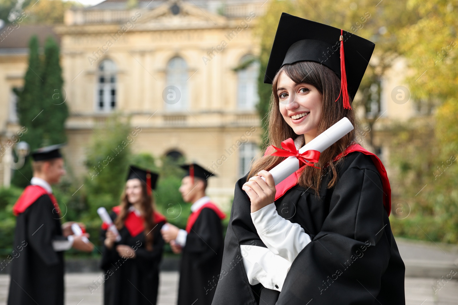 Photo of Happy students with diplomas after graduation ceremony outdoors, selective focus