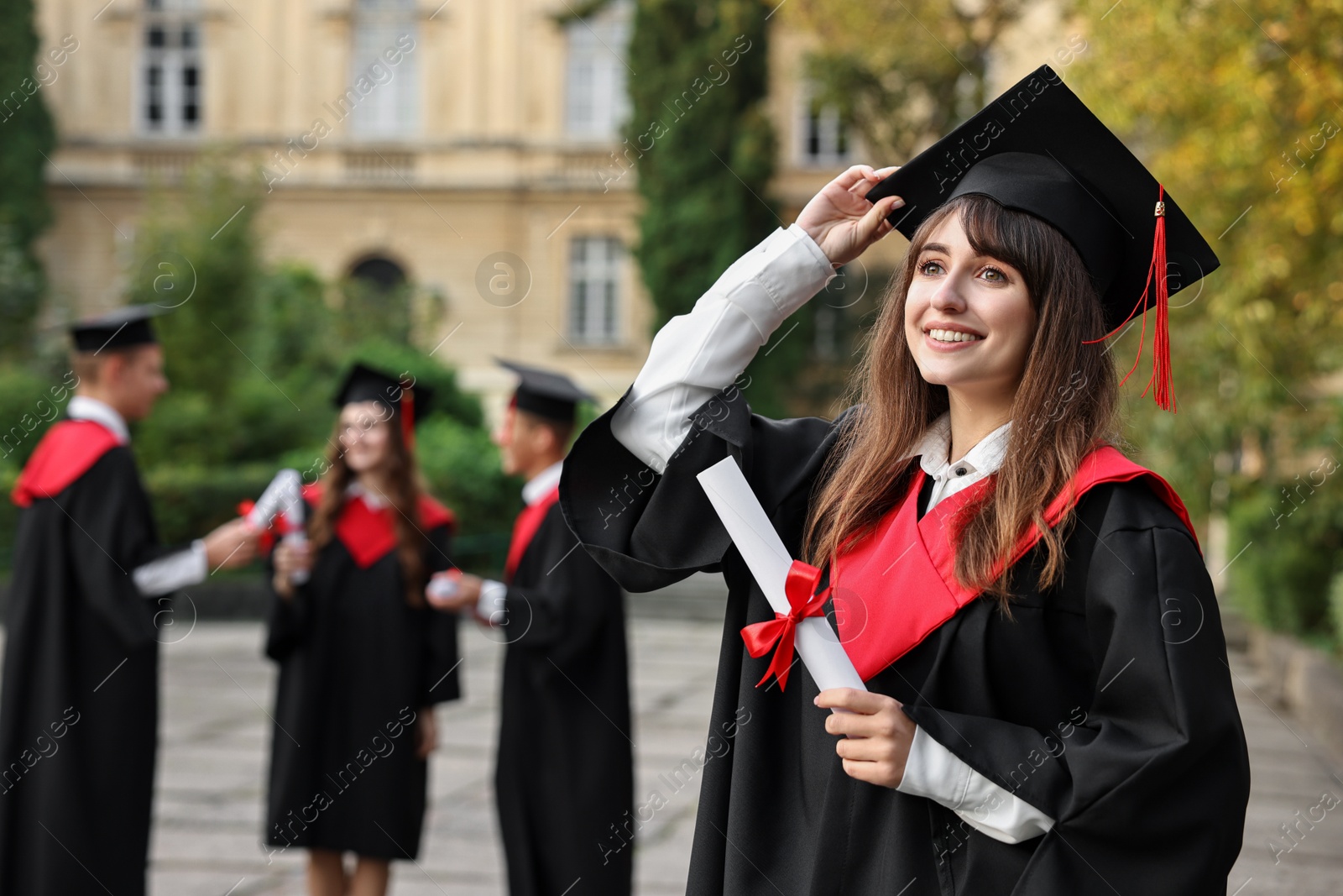 Photo of Happy students with diplomas after graduation ceremony outdoors, selective focus