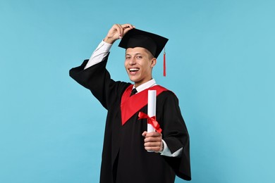 Photo of Happy student with diploma after graduation on light blue background