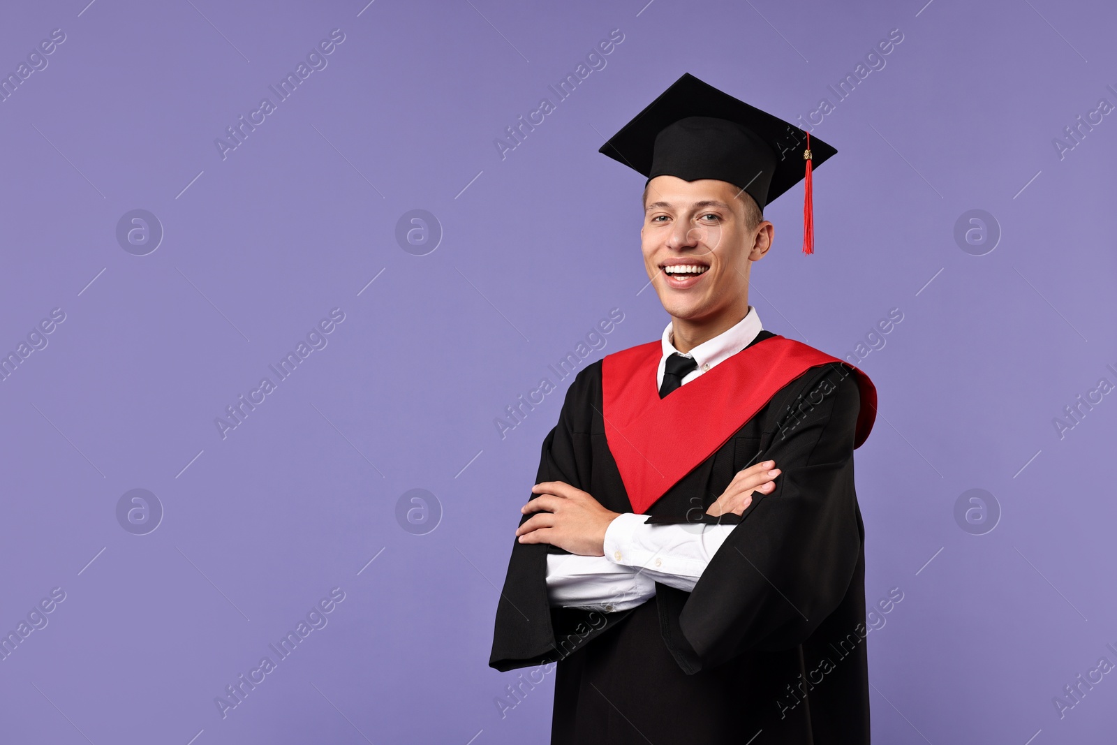 Photo of Happy student with crossed arms after graduation on violet background. Space for text