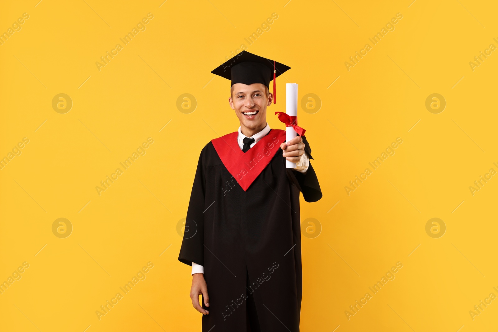 Photo of Happy student with diploma after graduation on orange background