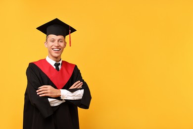 Photo of Happy student with crossed arms after graduation on orange background. Space for text