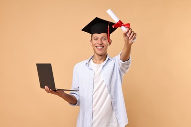 Happy student with diploma and laptop after graduation on beige background