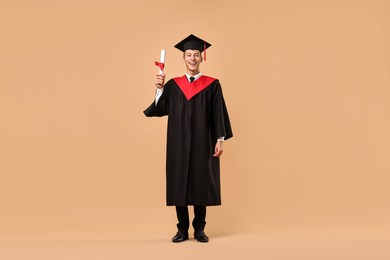 Photo of Happy student with diploma after graduation on beige background