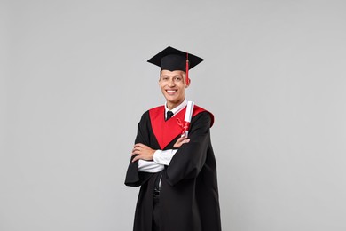 Photo of Happy student with diploma after graduation on grey background