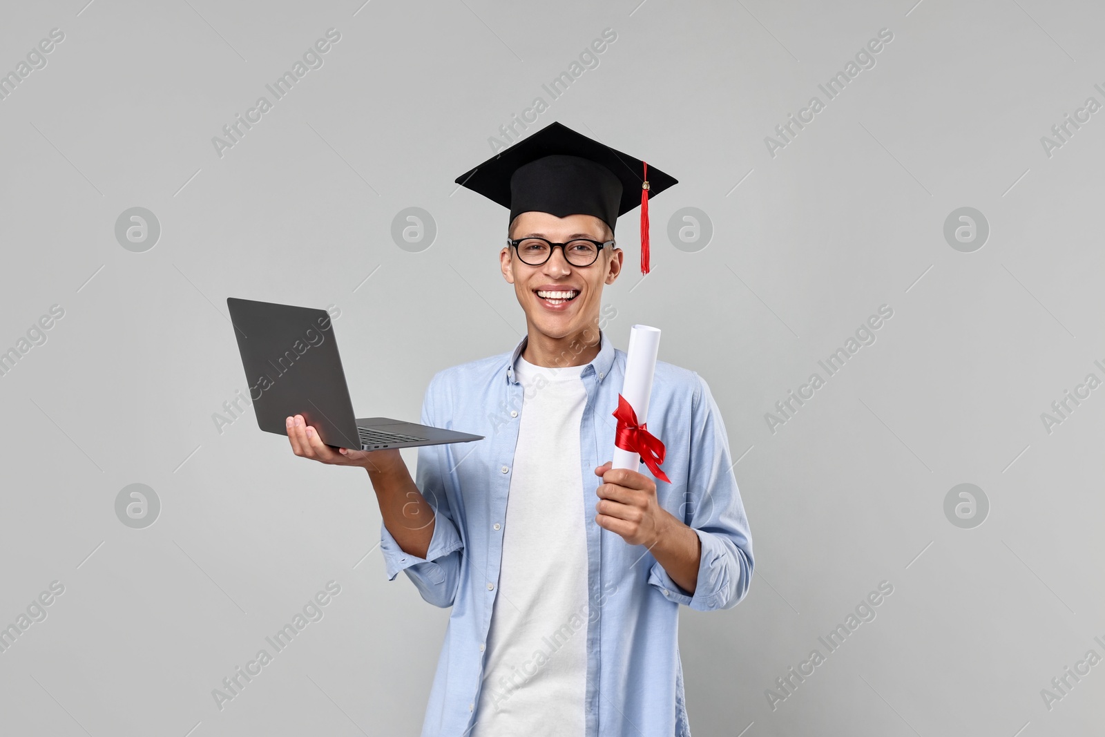 Photo of Happy student with diploma and laptop after graduation on grey background