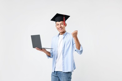 Photo of Happy student with laptop after graduation on light grey background