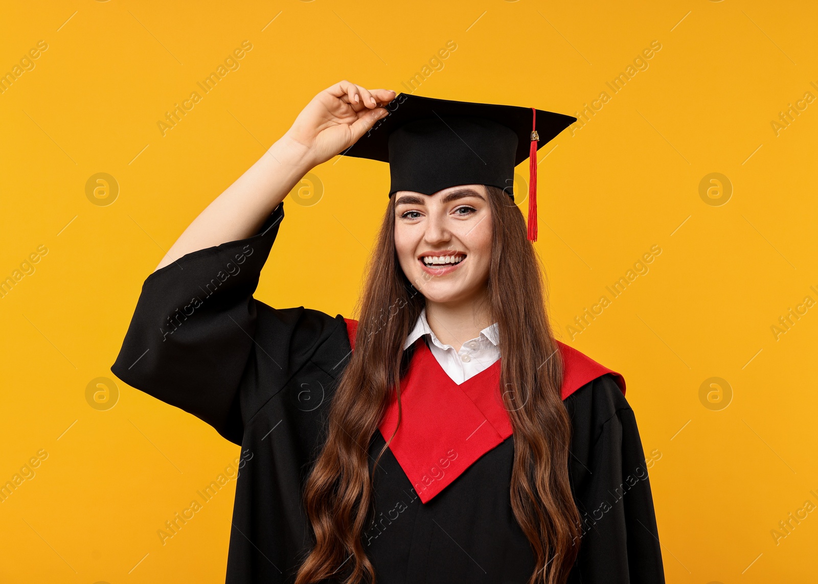 Photo of Happy student after graduation on orange background