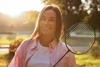 Photo of Happy young woman with badminton racket in park on sunny day