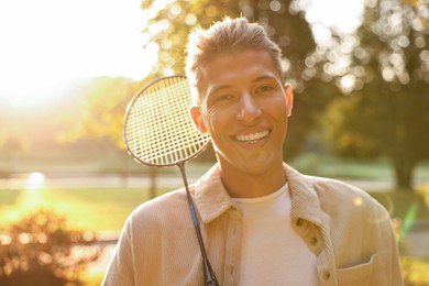 Photo of Happy young man with badminton racket in park on sunny day