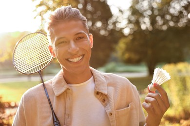 Photo of Happy young man with badminton racket and shuttlecock in park on sunny day