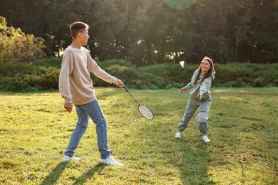 Young woman and man playing badminton in park on sunny day, selective focus