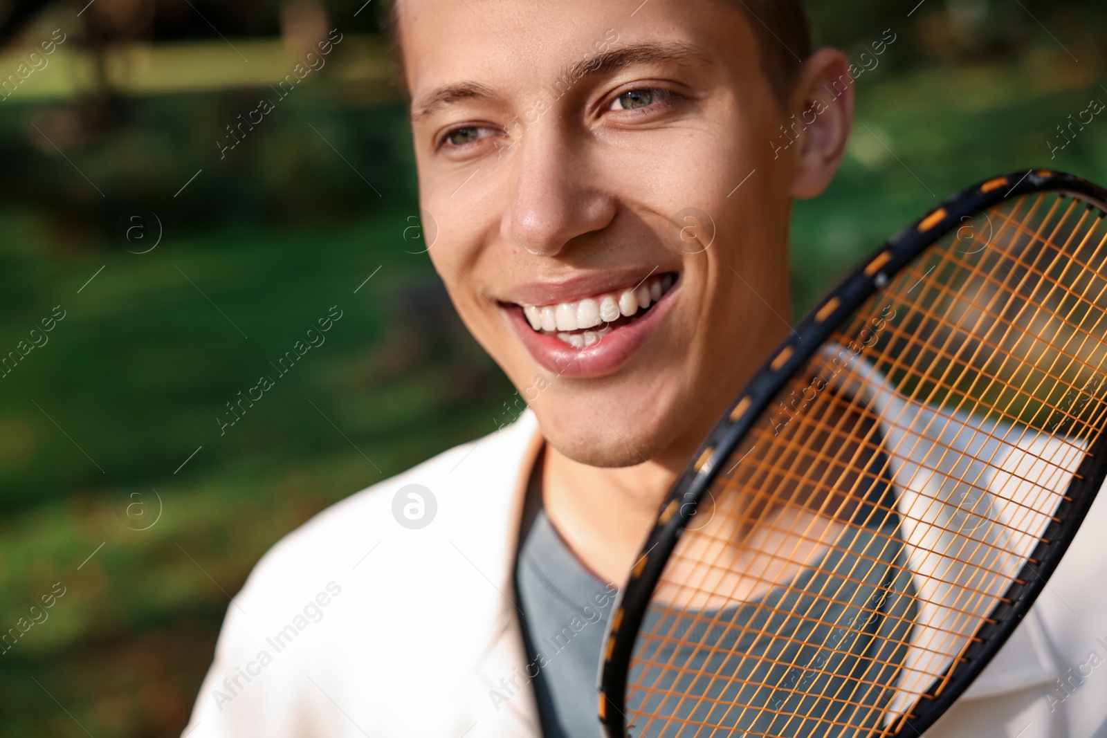 Photo of Happy young man with badminton racket in park