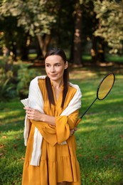 Photo of Young woman with badminton racket and shuttlecock in park