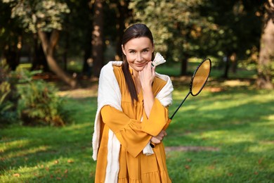 Photo of Young woman with badminton racket and shuttlecock in park