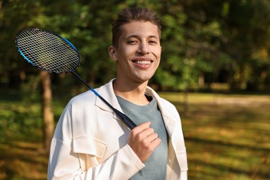 Photo of Happy young man with badminton racket in park