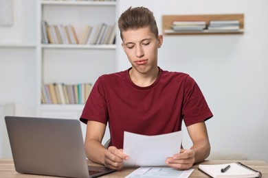 Photo of Tired student having stress before exam at table indoors