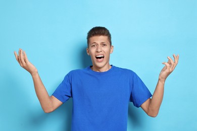 Photo of Emotional student having stress before exam on light blue background