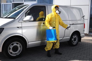 Pest control worker with spray tank near gray minibus outdoors