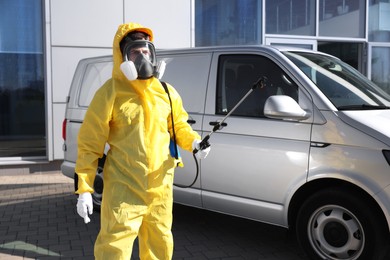 Photo of Pest control worker with spray tank outdoors