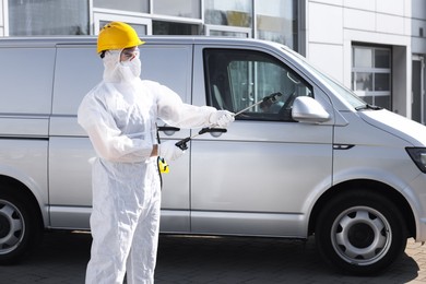 Pest control worker with spray tank near gray minibus outdoors