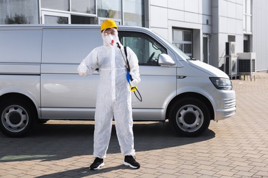 Photo of Pest control worker with spray tank showing thumbs up outdoors