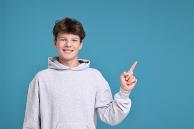 Photo of Portrait of happy teenage boy on light blue background, space for text