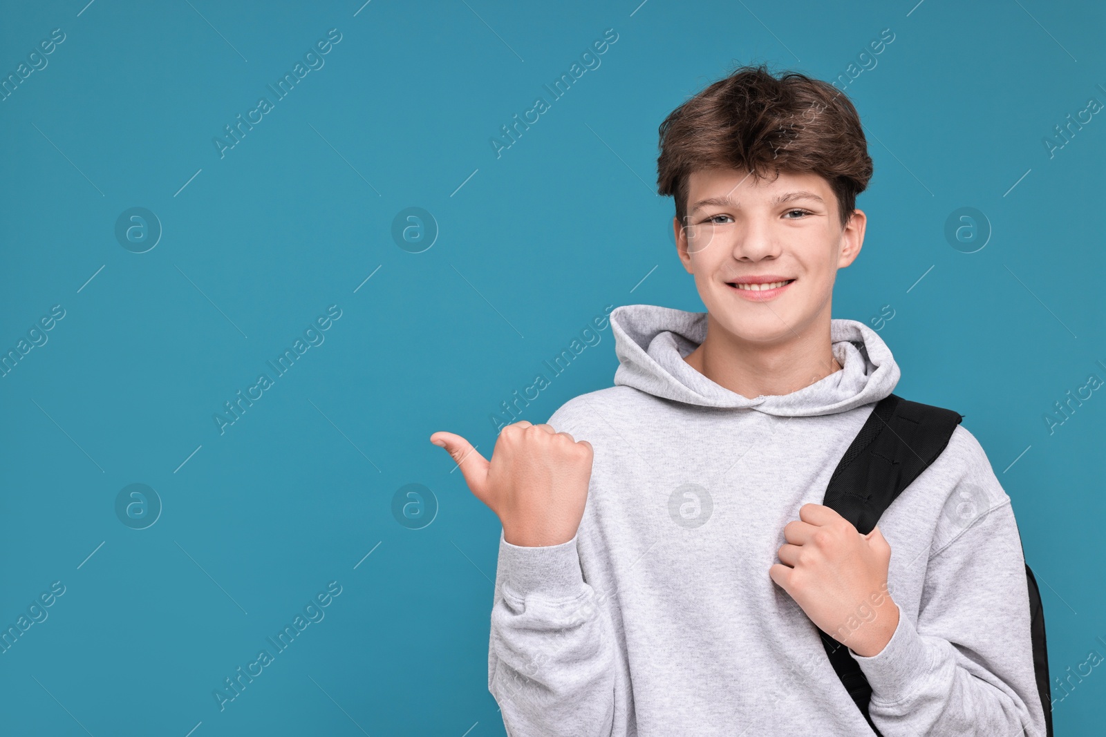 Photo of Teenage boy with backpack on light blue background, space for text