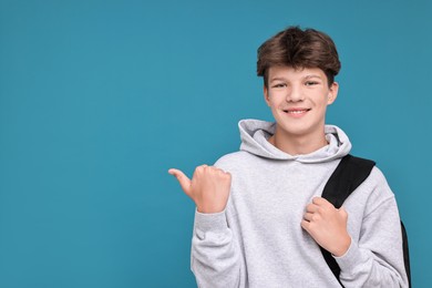 Photo of Teenage boy with backpack on light blue background, space for text