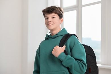 Photo of Portrait of happy teenage boy with backpack indoors