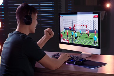 Photo of Young man playing video game with keyboard at wooden table indoors