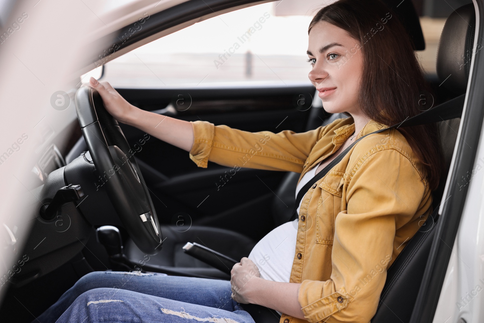 Photo of Pregnant woman with safety belt driving car