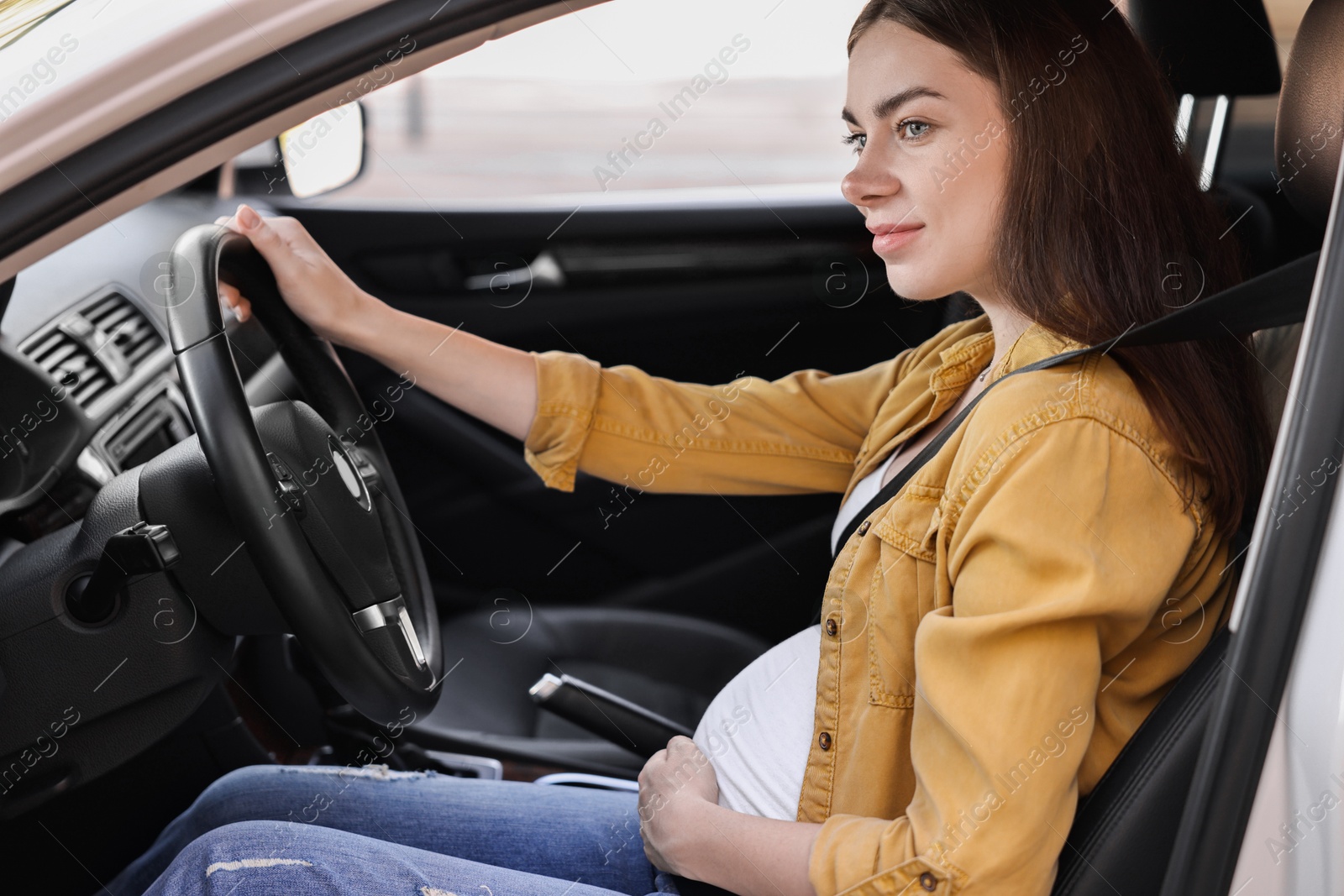 Photo of Pregnant woman with safety belt driving car