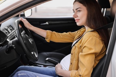 Photo of Pregnant woman with safety belt driving car