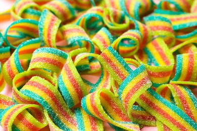 Photo of Tasty rainbow sour belts on pink background, closeup