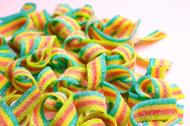 Photo of Tasty rainbow sour belts on pink background, closeup