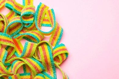 Photo of Tasty rainbow sour belts on pink background, top view. Space for text