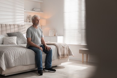 Photo of Lonely senior man sitting on bed at home