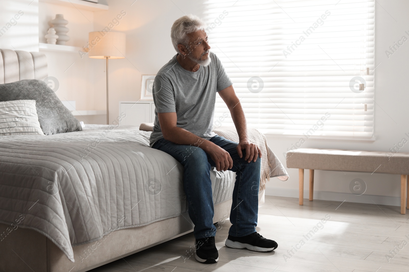 Photo of Lonely senior man sitting on bed at home