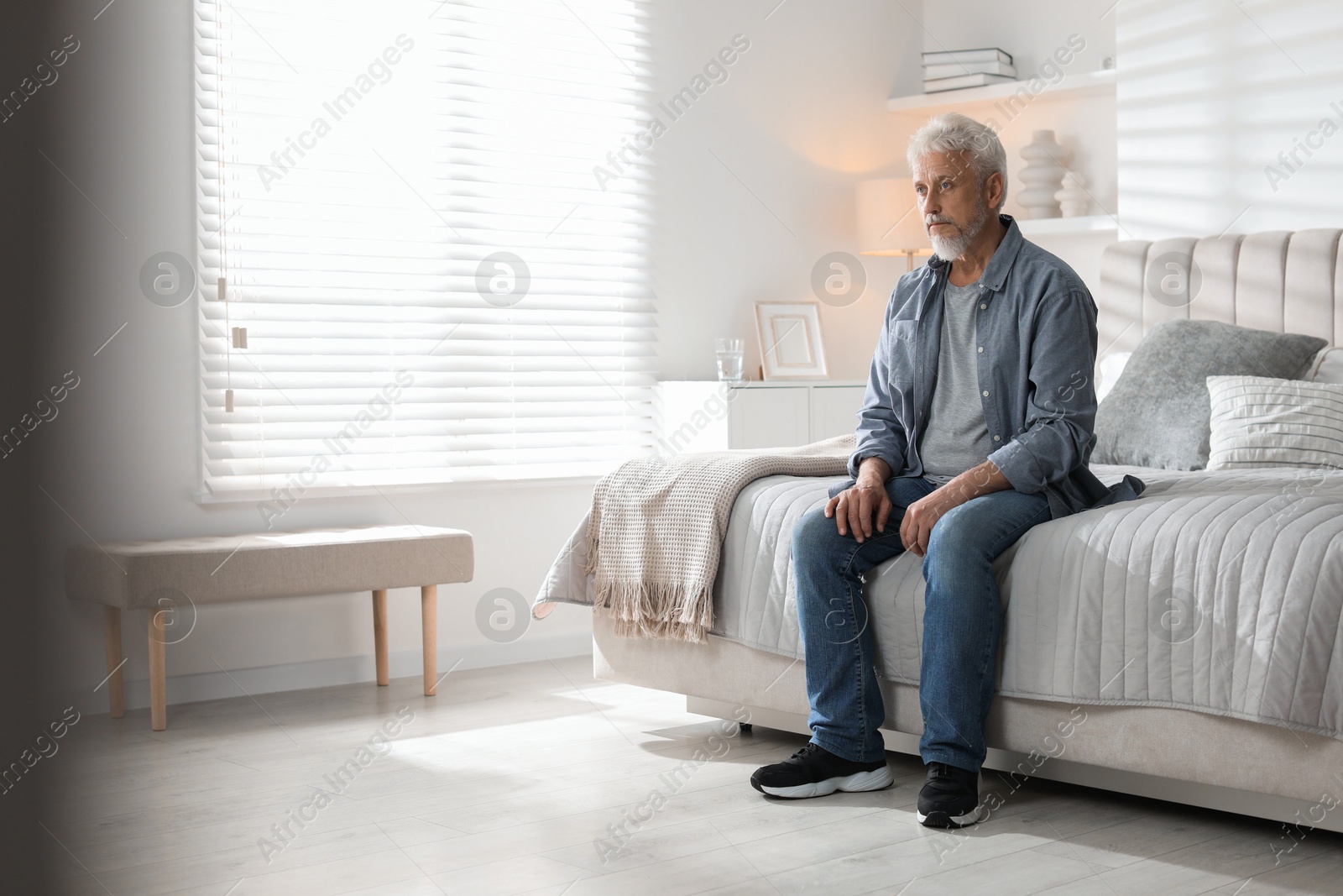 Photo of Lonely senior man sitting on bed at home