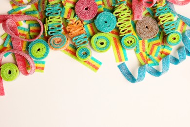 Different tasty sour belts on beige background, top view