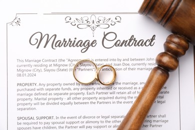 Photo of Marriage contract, gavel and golden rings, top view