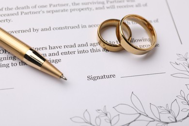 Photo of Marriage contract, pen and golden rings, closeup